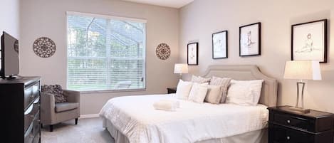 A bedroom with a bed, nightstands, a dresser, a ceiling fan, and wall art.