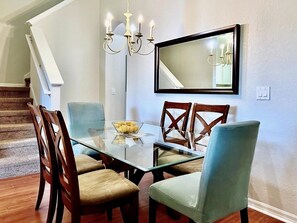 A dining area with a glass table, wooden chairs, and a chandelier. - Spacious 4bd Th Regal Palms 2530ca 4 Bedroom Townhouse by RedAwning (Davenport)