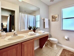 A bathroom with a sink, mirror, toilet, and a window. - Spacious 4bd Th Regal Palms 2530ca 4 Bedroom Townhouse by RedAwning (Davenport)