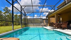 A swimming pool with a glass enclosure, surrounded by outdoor furniture and a view of trees and sky. - Watersong Resort 6bd Pool Hm,2 Master Suites-956oc 6 Bedroom Home by RedAwning (Davenport)