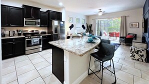A modern kitchen with dark cabinets, stainless steel appliances, and a central island. - Luxury 5d Spa Gm Pool Hm Solterra Resort-5165ac 5 Bedroom Home by RedAwning (Davenport)