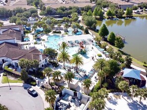 A residential area with a large swimming pool, palm trees, and houses. - Lovely New Pool Home At Windsor At Westside-2167tc 8 Bedroom Home by RedAwning (Kissimmee)