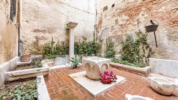 A courtyard with a brick floor, stone benches, and potted plants. - La Dogaressa Guest House (Venice)