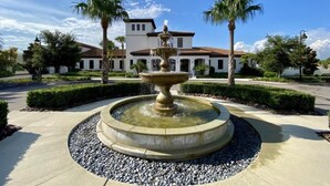 A fountain in a circular stone basin with a building in the background. - Gorgeous 4bd Th Pool Windsor At Westside-2018ww 4 Bedroom Home by RedAwning (Kissimmee)