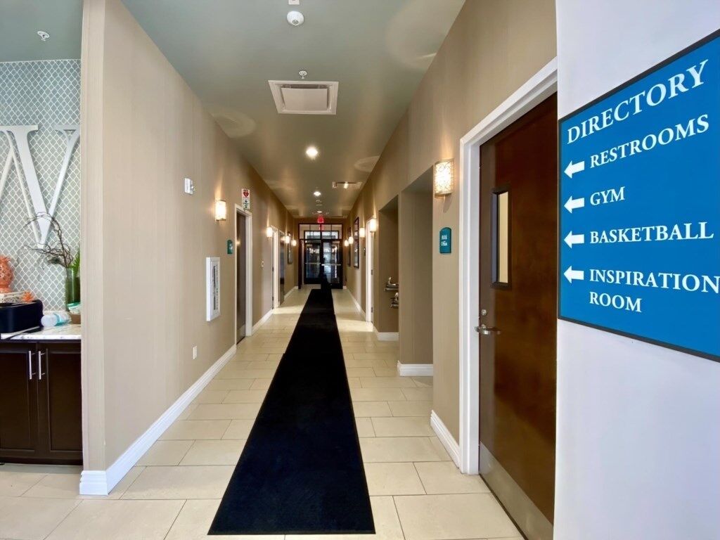 A hotel corridor with a directory sign listing amenities like restrooms, gym, basketball, and an inspiration room.