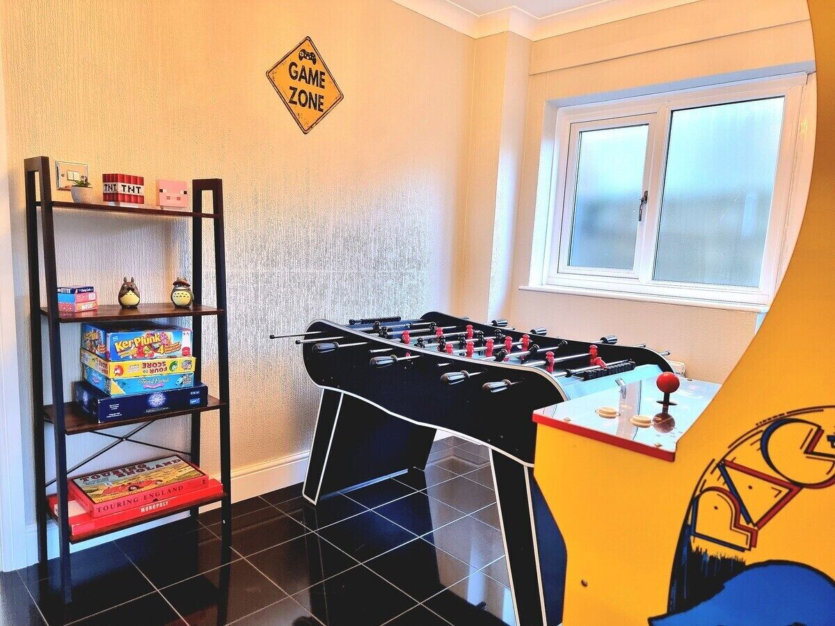 Une pièce avec un baby-foot, une étagère remplie de jeux de société et un panneau indiquant « ZONE DE JEUX ».
