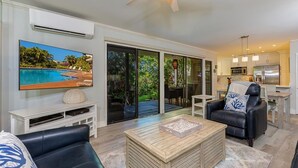 A modern living room with a flat-screen TV, a wooden coffee table, and a black leather sofa. - Wailea Ekolu 1603 2 Bedroom Condo (Kihei)