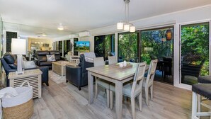 A modern living room with a dining area, large windows, and a view of the outdoors. - Wailea Ekolu 1603 2 Bedroom Condo (Kihei)