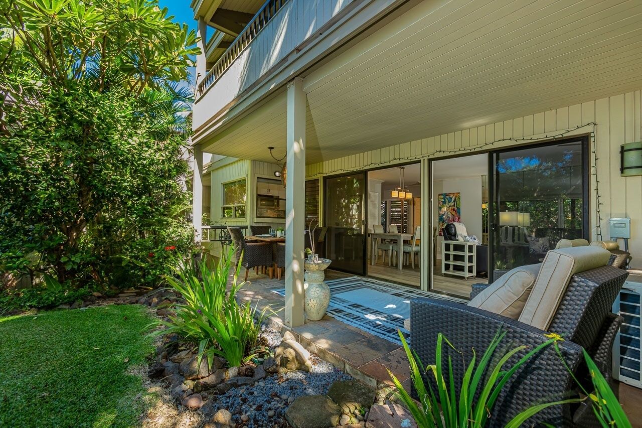 A covered outdoor patio with a dining area, a kitchen, and a living room with a sofa and chairs.