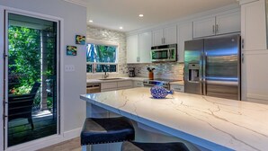 A modern kitchen with white cabinets, stainless steel appliances, and a marble countertop. - Wailea Ekolu 1603 2 Bedroom Condo (Kihei)