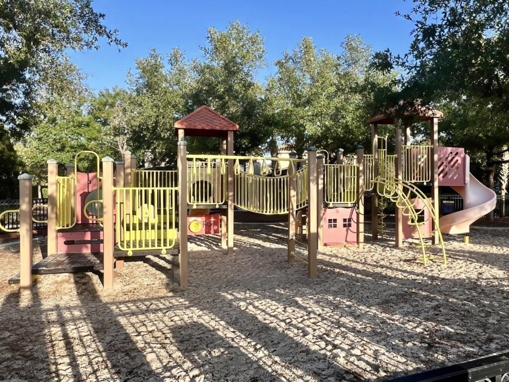 Ein Spielplatz mit Rutsche, Klettergerüsten und einem überdachten Bereich.