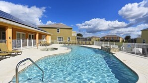 A swimming pool with a curved design, surrounded by a tiled deck and a fence. - Beautiful 3-bed Villa 10 Minutes From Disney-17440 Serenity Resort 3 Bedroom Townhouse by RedAwning (Clermont)