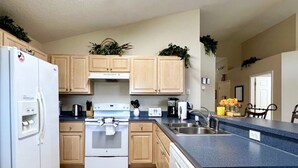 A modern kitchen with wooden cabinets, a white refrigerator, a stove, and a sink. - Cozy 3 Br 2 Bath Villa With Splash Pool-335kd 3 Bedroom Home by RedAwning (Davenport)