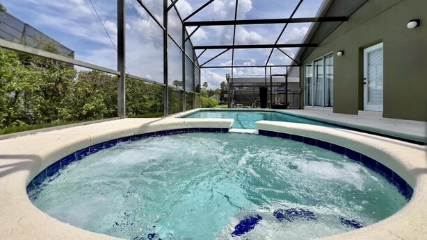 A hot tub with a glass enclosure, a pool, and a covered patio area. - Lovely 4bd Gm Spa Pool Hm Glenbrook-1616msd 4 Bedroom Villa by RedAwning (Clermont)