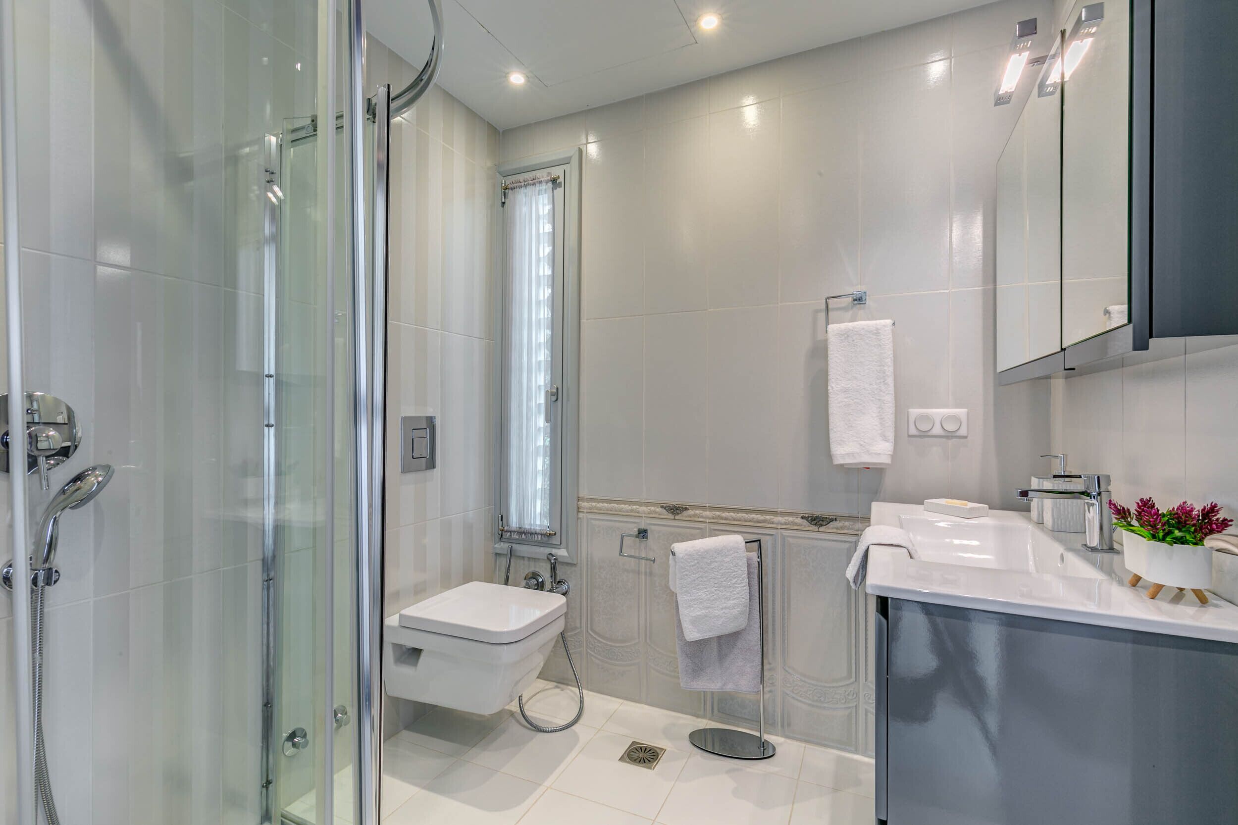 A modern bathroom with a glass-enclosed shower, a white sink, and a mirror cabinet.