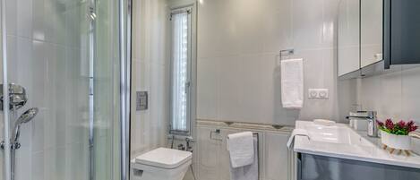 A modern bathroom with a glass-enclosed shower, a white sink, and a mirror cabinet.
