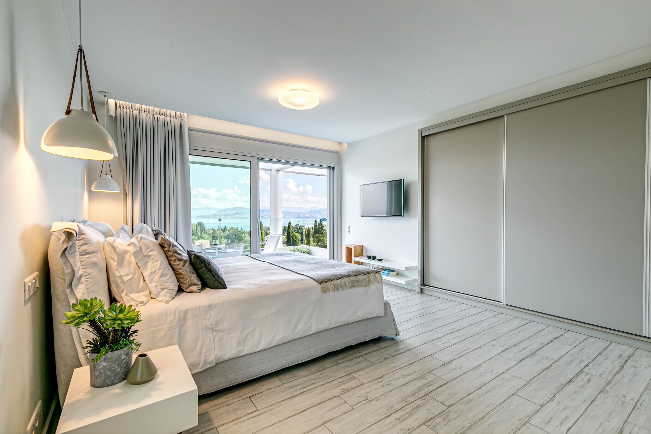 Une chambre moderne avec un grand lit, une télévision et une vue sur l’extérieur.