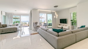 Ein modernes Wohnzimmer mit einer großen Couch, einem Essbereich und einem an der Wand befestigten Fernseher.