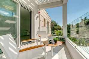 Enjoy the serene views of lush greenery from this stylish balcony with a comfortable seating area.