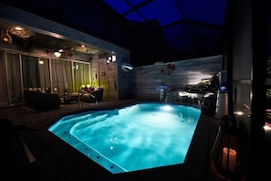 Una piscina coperta riscaldata con un pontile in legno, poltrone relax e un murale a tema squalo.