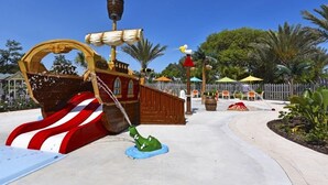 A pirate-themed play area with a ship-shaped slide, a green crocodile figure, and a wooden fence.