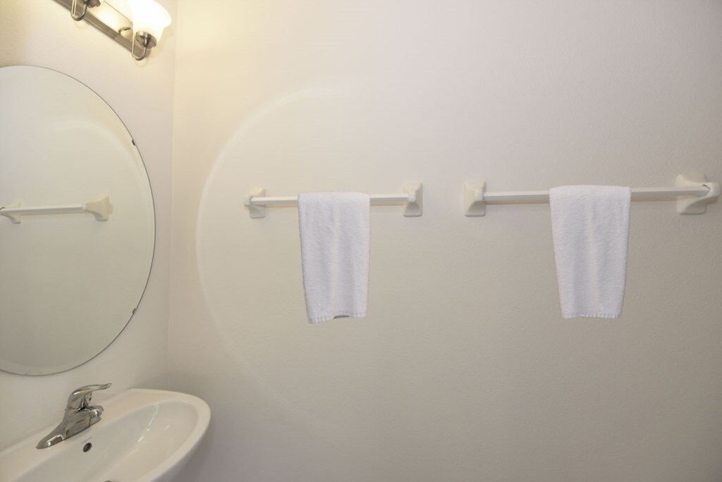 A bathroom with a round mirror, a sink, and two towels hanging on a towel rack.