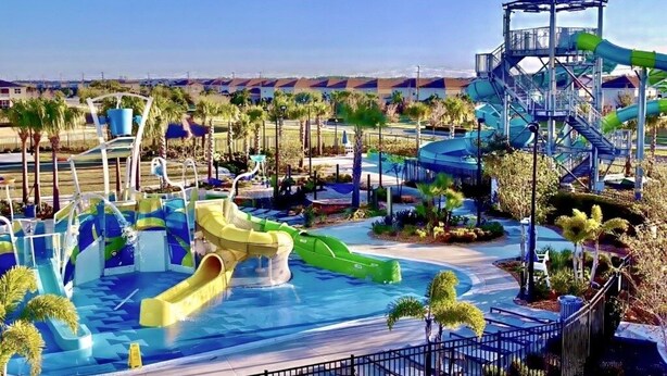 A water park with multiple slides and a large pool area surrounded by palm trees.