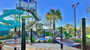 A water park with slides, a lookout tower, hammocks, and palm trees.