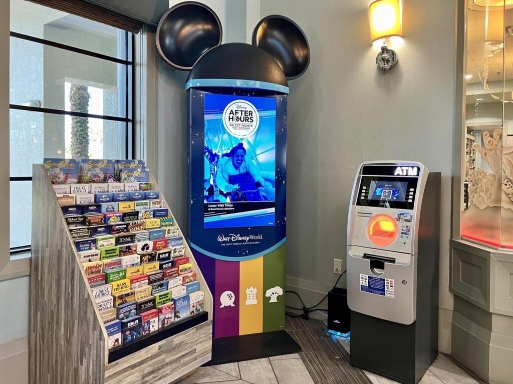A Disney After Hours sign, a selection of Disney-themed books, and an ATM machine.