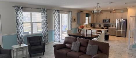 A living room with a brown sofa, a coffee table, and a dining area with a table and chairs.