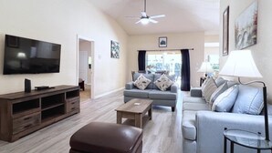 Un salon moderne doté d’un téléviseur à écran plat, d’un ventilateur de plafond, d’un ensemble de canapés, d’une table basse et d’un meuble pour téléviseur.