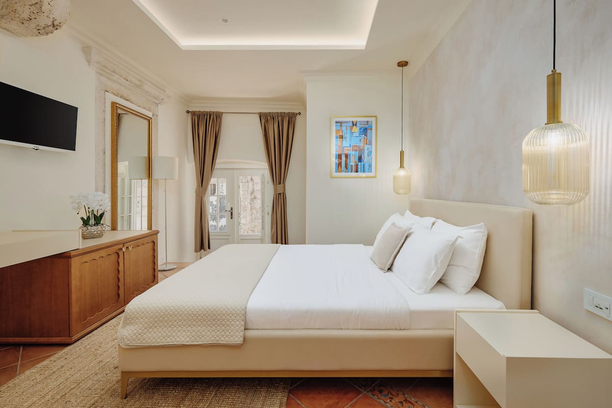 Ein Schlafzimmer mit einem großen Bett, einer hölzernen Kommode, einem Flachbildfernseher und einem Bild an der Wand.