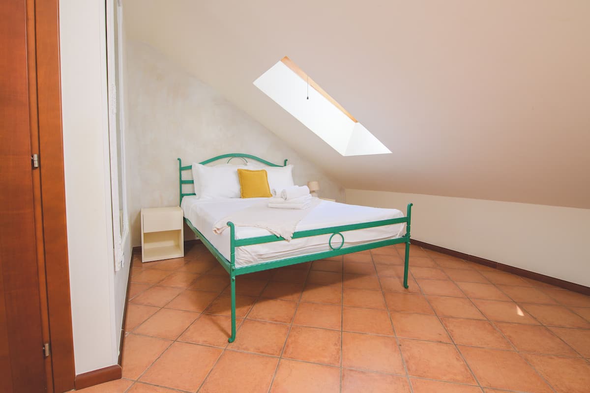 Ein Einzelbett in einem Zimmer mit schrägem Dach und einem Dachfenster.