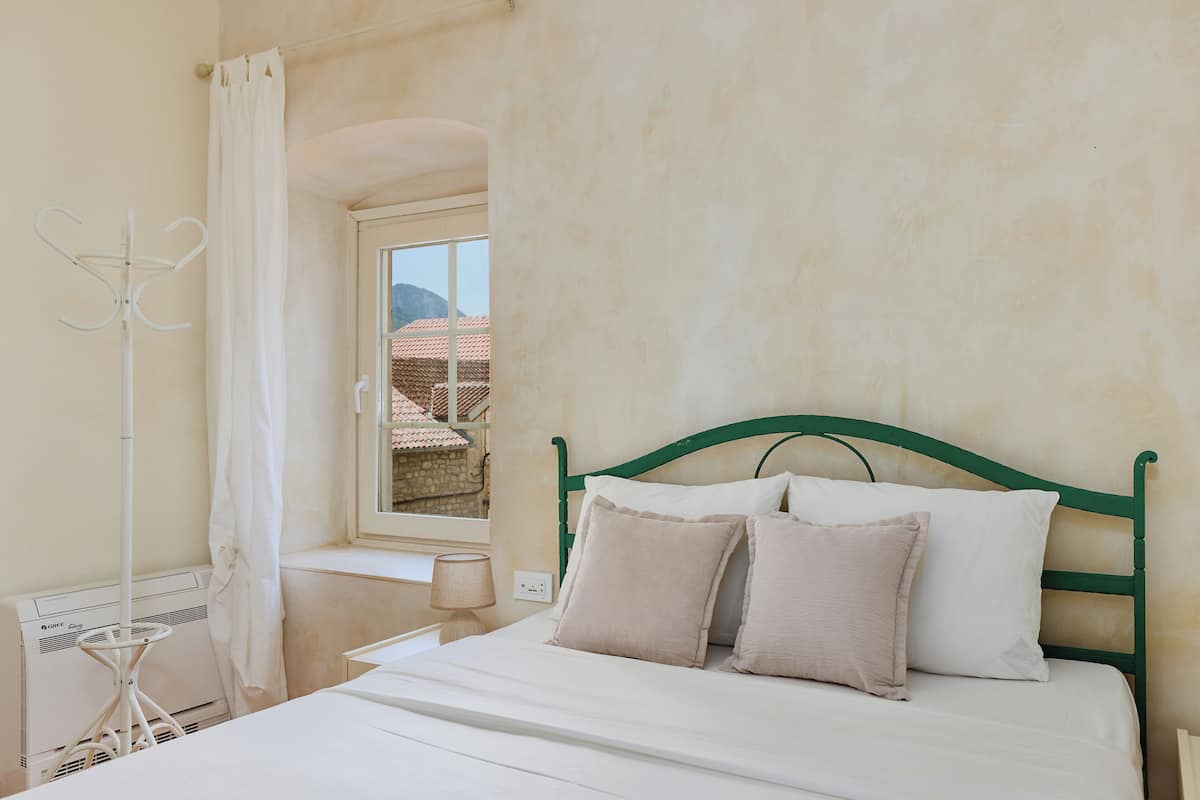 Ein Schlafzimmer mit Bett, Fenster und Heizkörper.