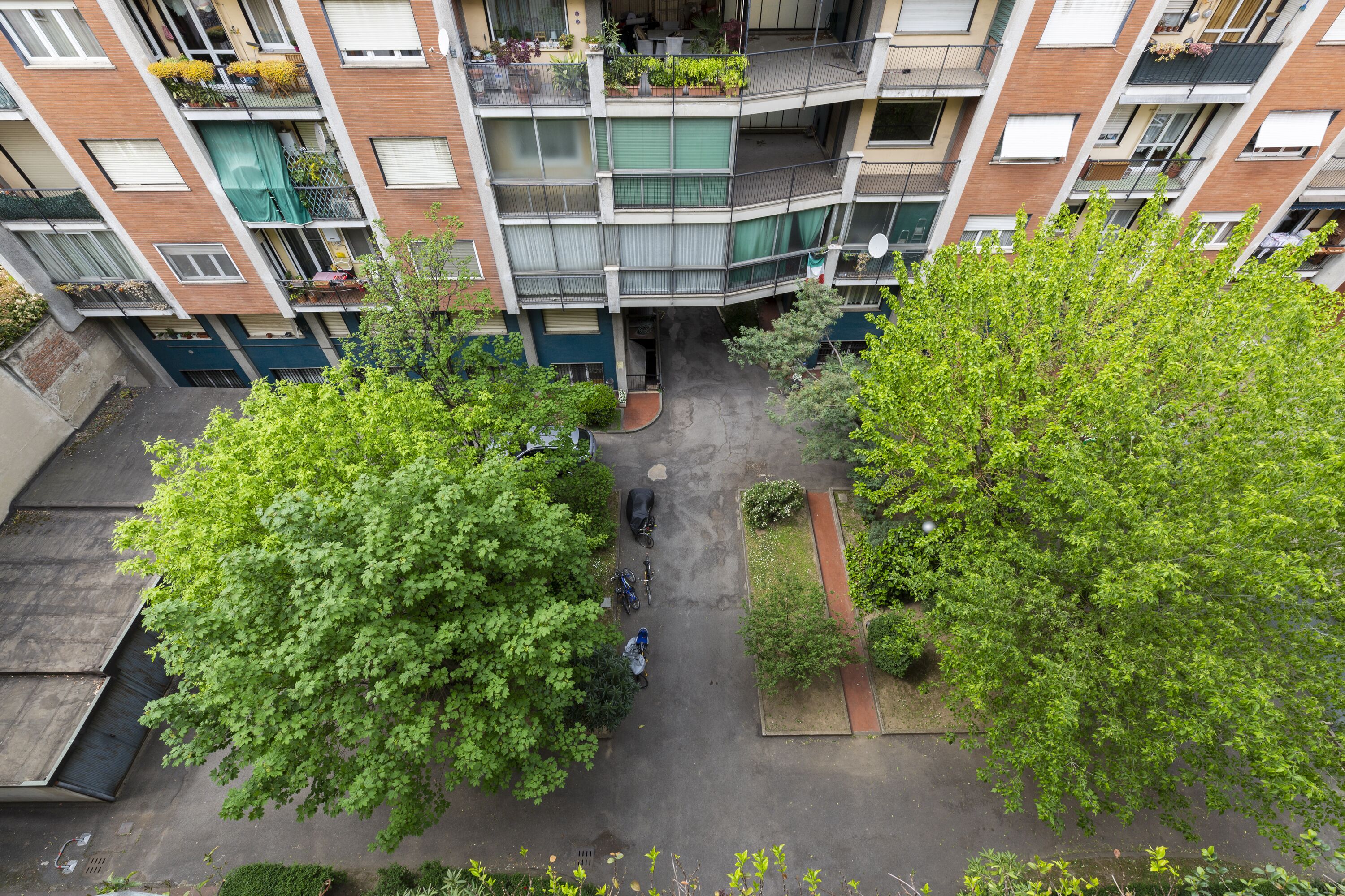 A multi-story residential building with balconies, a courtyard, and surrounding greenery.