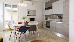 A modern kitchen with white cabinets, a dining table with chairs, and a fruit bowl. - notaMI - CASA RELAX - Central Station (Milan)