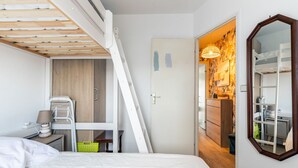 Een slaapkamer met een stapelbed, een bureau met stoel, en een kledingkast.
