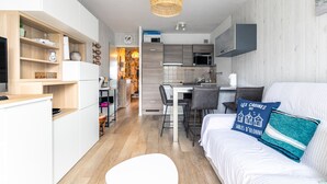 Een compacte woonruimte met een kitchenette, een eethoek en een bed.