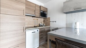 Een moderne keuken met houten kastjes, een ingebouwde magnetron en een vaatwasser.