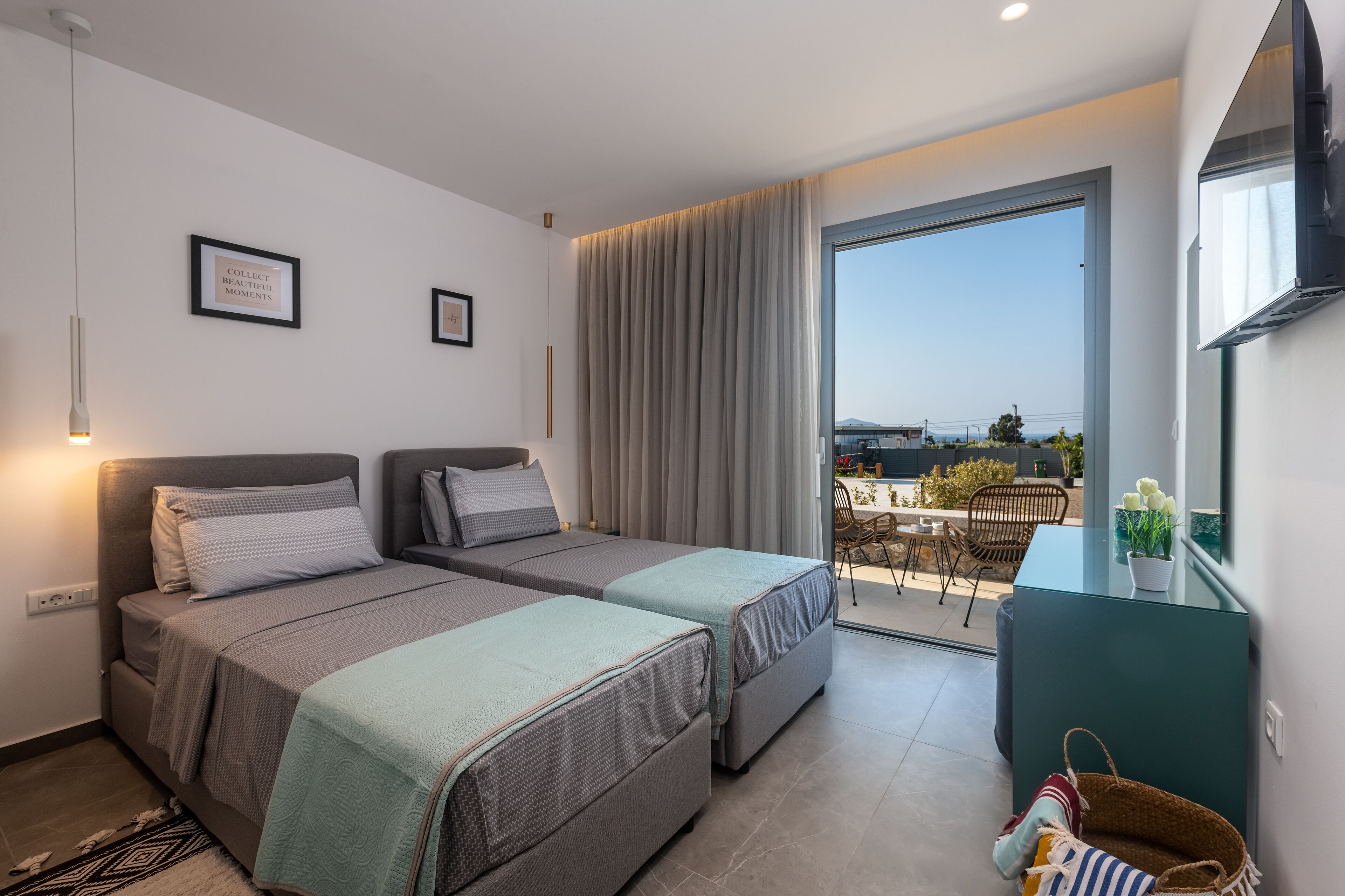 Une chambre d’hôtel moderne avec deux lits, un balcon offrant une vue agréable et un coin repas visible à travers la porte vitrée.