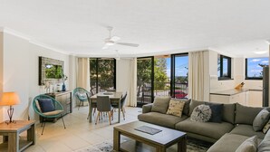 A modern living room with a sofa, coffee table, dining table, chairs, and a balcony with a view. - Porta Pacifique 3 - Renovated Beachfront Bilinga (Bilinga)