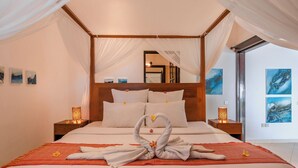 A four-poster bed with a canopy, a heart-shaped towel arrangement, and artwork on the walls. - Gorgeous beachfront Villa Jasmine, Lovina! (Kecamatan Banjar)