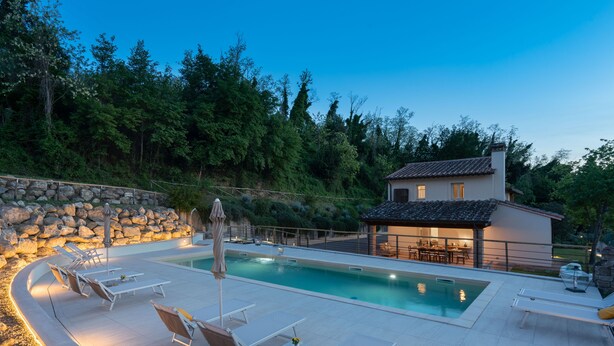 A swimming pool with lounge chairs and a stone wall.