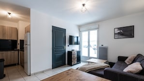 A compact living space with a kitchenette, a dining area, a sofa, and a TV mounted on the wall. - Appartement Maria (Briançon)