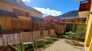 A courtyard with a gravel path, a wooden fence, and a row of chairs. - Appartement Maria (Briançon)
