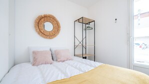 A bedroom with a bed, a round mirror, and a metal shelving unit. - Appartement Maria (Briançon)