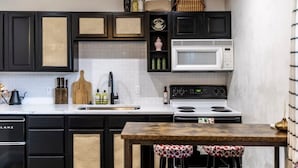 Una cocina con armarios negros, un microondas blanco y una mesa de madera.
