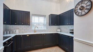 A modern kitchen with dark cabinetry, white subway tiles, and a large wall clock.