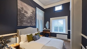 A bedroom with a bed, nightstand, lamp, and a painting on the wall.