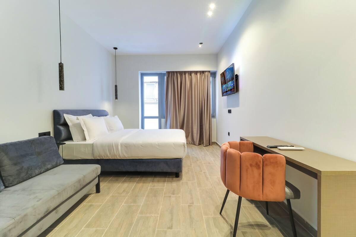 Ein modernes Hotelzimmer mit Bett, einer Couch, einem Schreibtisch und einem Fernseher.
